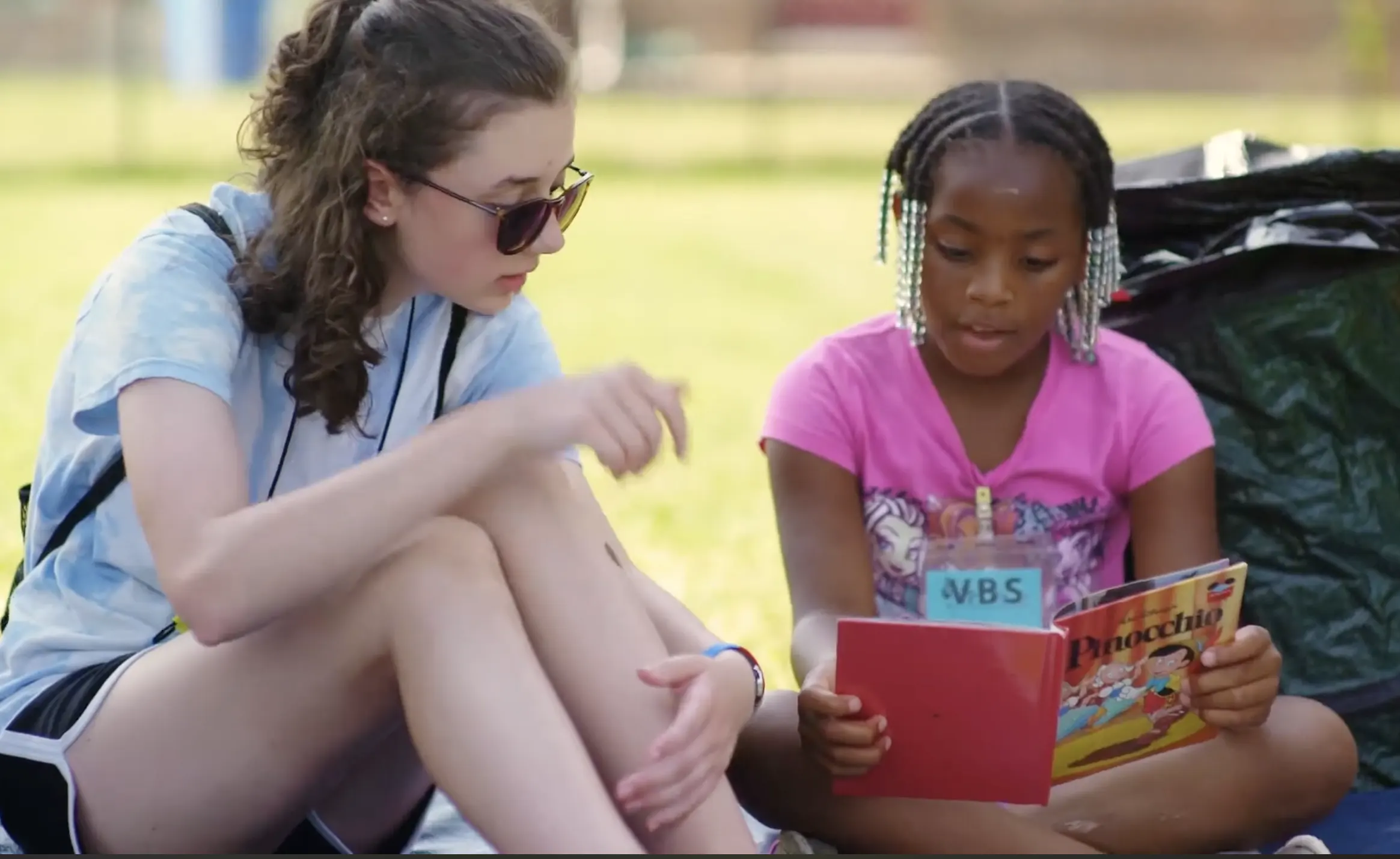 a teenage girl reading with a young child
